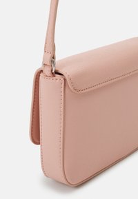 Różowa syntetyczna torba o gładkiej fakturze, prostokątnym kształcie i zamknięciu na klapę. Posiada cienki pasek na ramię oraz przeszycia dekoracyjne.