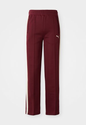 Bordeauxrode sweatpants van een textuurstof, met witte zijstrepen en een elastische tailleband. Inclusief ritszakken aan de zijkant en een logo-detail.