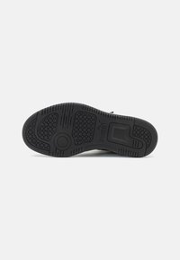Puma sneaker zool in zwart rubber met een gestructureerd grippatroon, voorzien van een cirkelvormig gegraveerd logo en verschillende profielontwerpen voor tractie.