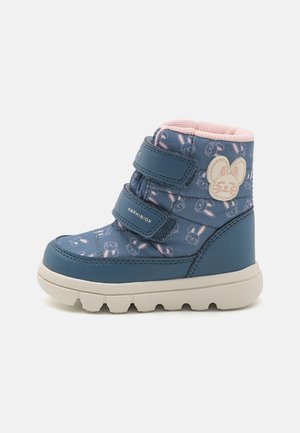 Botte à chevilles imperméable bleue avec doublure rose, bandes velcro et motif de lapin. Présente une surface texturée et une semelle blanche épaisse.