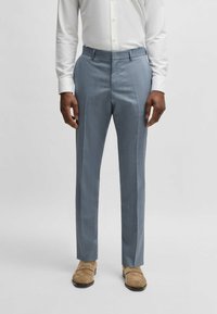 Light blue tailored trousers with a textured weave, flat front, and pressed creases. Paired with tan shoes and a white button-up shirt.