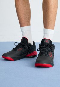 Černé sportovní boty s červenými akcenty, s vrchní částí z prodyšné síťoviny, perforacemi a viditelnou vzduchovou tlumicí jednotkou v podrážce.