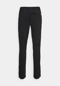 Pantalons noirs en tissu extensible, avec une taille ajustée, des jambes droites, des poches latérales zippées et des fentes aux chevilles pour faciliter le mouvement.