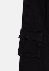 Black cargo pants featuring a textured fabric, multiple pockets, and stitching details, showcasing a functional and casual design.