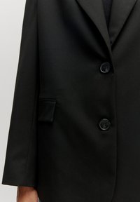 Zwarte blazer met een notch-lapel, twee knopen en een zijzak, gemaakt van een gladde, gestructureerde stof.