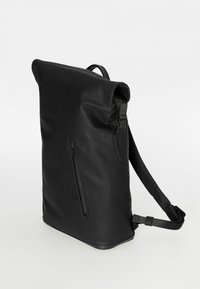 Schwarzer Rucksack mit Rollverschluss, verstellbaren Trägern, seitlicher Reißverschlusstasche, glatter Oberfläche und geprägt aufgedrucktem Markenzeichen auf der Vorderseite. Hergestellt aus robustem Material.