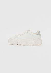 Sneaker in pelle bianca con punta arrotondata, suola spessa e rigata, e un accento argento sul tallone. Presenta un design con lacci e una texture liscia.