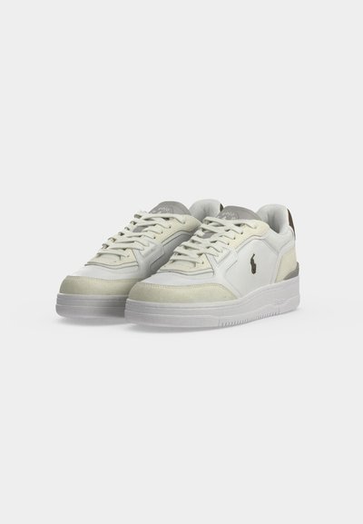 Ζευγάρι λευκά sneakers χαμηλού πάτου με μπεζ σουέντ λεπτομέρειες, κούμπωμα με κορδόνια και μικρό σκούρο λογότυπο αλόγου στο πλάι.
