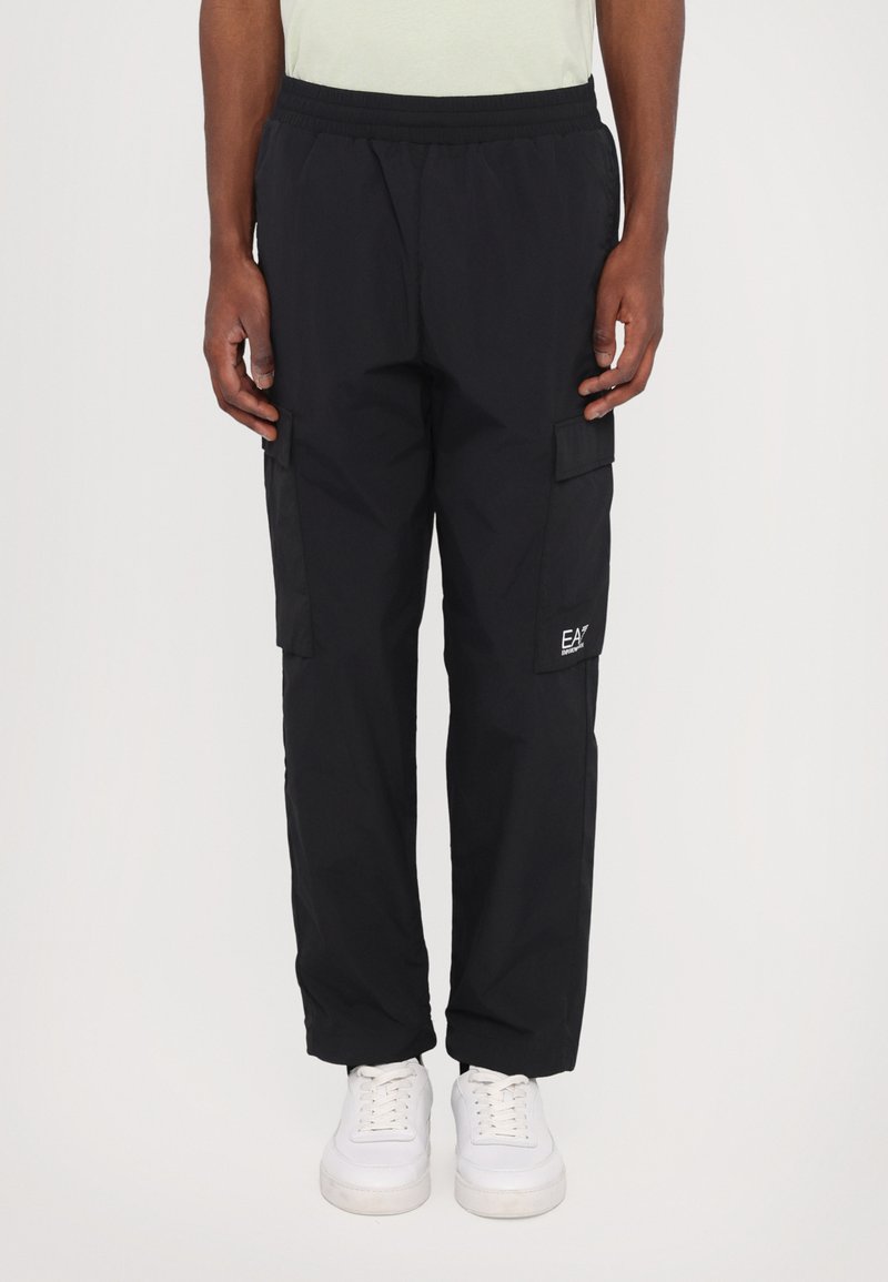 Pantalons cargo noirs avec une taille élastique, deux poches latérales et un petit logo EA7 sur la jambe gauche. Fabriqués en tissu léger.