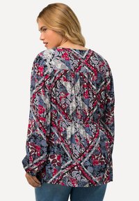 Langärmlige Bluse mit einem mehrfarbigen Paisleymuster in Rot, Blau und Weiß. Leichter Stoff mit lockerer Passform und gerafftem Rückendetail.