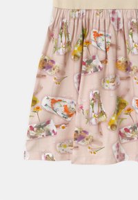 Jasnoróżowy materiał z kolorowym wzorem lodów na patyku w kształcie kwiatów, z widoczną marszczoną talią i gładką teksturą.