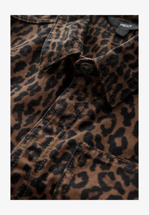 Brązowa koszula w panterkę z czarnymi plamami, z kołnierzykiem, zapięciem na guziki i ozdobnymi przeszyciami. Wykonana z teksturowanej tkaniny.