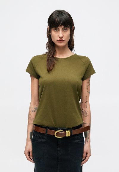 T-shirt à manches courtes vert olive avec un col rond, texture lisse, porté avec une jupe en denim foncé et une ceinture marron avec une boucle dorée.