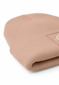 Light pink knitted beanie with ribbed texture, folded cuff, and a small branded tag showing a logo. Soft and smooth fabric finish.