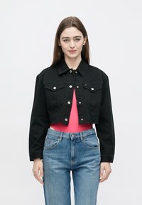 Mustast kärbitud teksajakk hõbedaste nuppude, rinnataskute ja terava kraega, kombineeritud helesiniste teksade ja roosa toppiga.