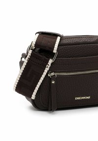 Hnědá textured syntetická crossbody taška s dekorativním popruhem a stříbrným kováním. Obsahuje kapsu na zip a akcent s zlatým logem.