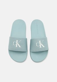 Sandales à glissière bleu clair avec une sangle en tissu texturé arborant le logo blanc "CK". Semelle en caoutchouc lisse pour un confort optimal. Design simple et minimaliste.