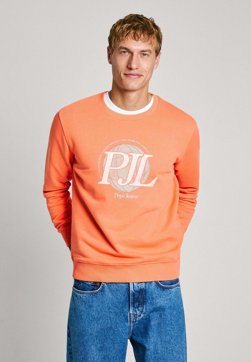Sudadera naranja de cuello redondo, con un estampado gráfico blanco y el logo "Pepe Jeans". Combinada con unos jeans de mezclilla azul.