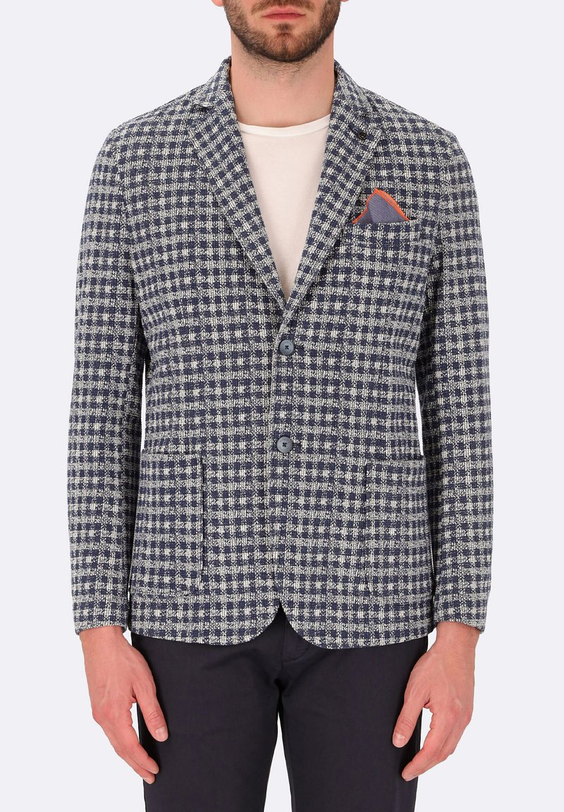 Blazer a scacchi bianco e blu navy con due tasche frontali, rever a punta e fazzoletto rosso, con chiusura a due bottoni.