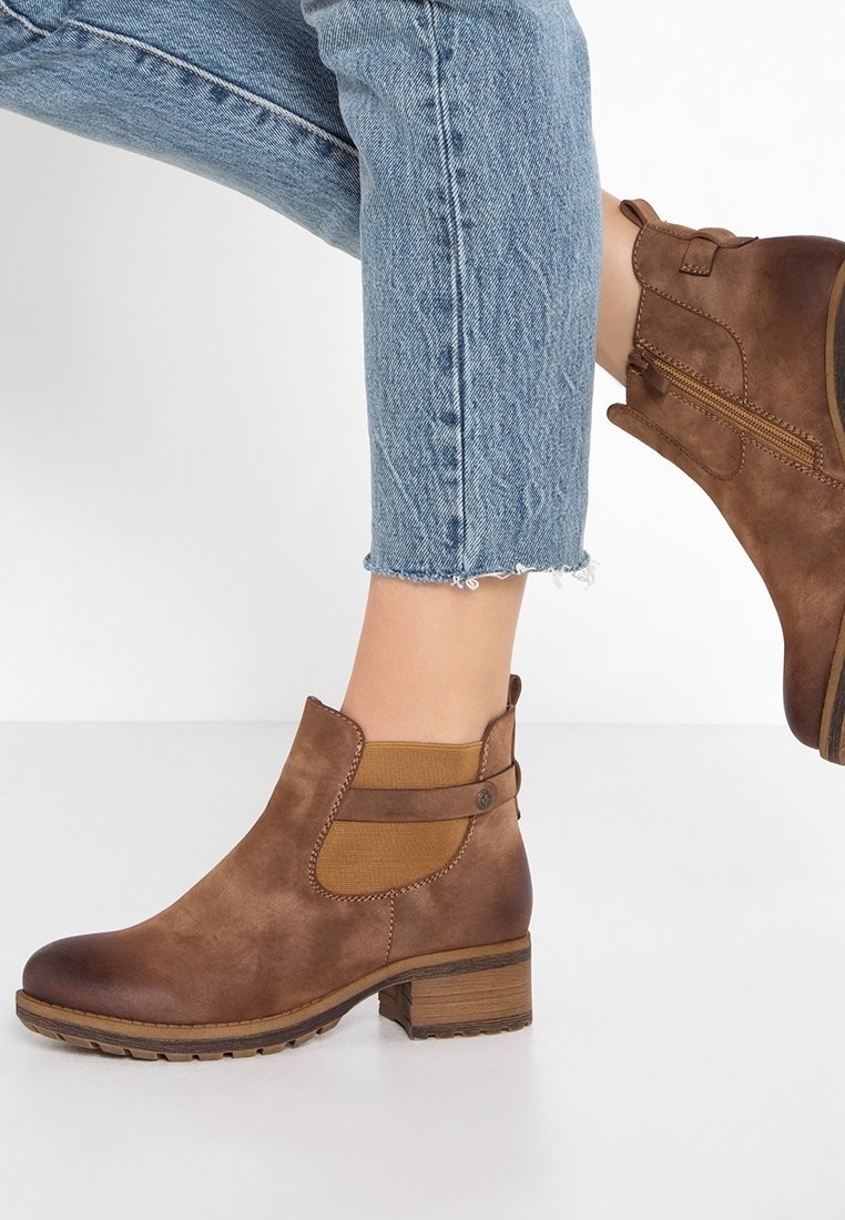 Bottines marron à talons carrés portées avec un jean court bleu clair sur fond blanc.