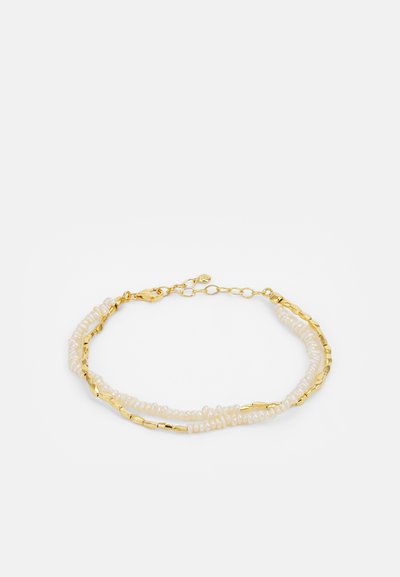 Bracelet en chaîne dorée avec des perles blanches et des accents dorés texturés, présentant un design superposé et une fermeture à grappin.
