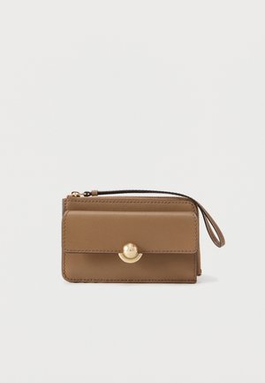 Portafoglio da polso compatto in pelle marrone con patta frontale, chiusura circolare dorata e scomparto con cerniera su uno sfondo bianco semplice.