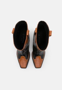 Stivali vegan neri e marroni alla caviglia con punta appuntita e texture in rilievo a effetto coccodrillo. Presentano due anelli laterali per una facile indossabilità. Taglia 36.