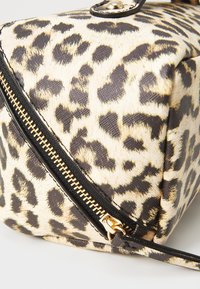 Tasche aus beigem und schwarzem Kunstleder mit Leopardenmuster, ausgestattet mit goldenen Reißverschlussdetails und einer strukturierten Form mit Klappenverschluss.