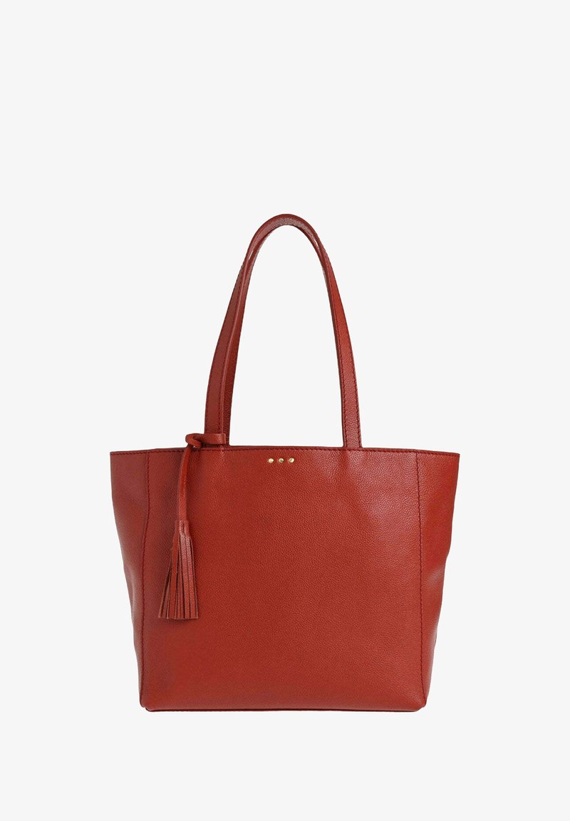 Sac fourre-tout en cuir rouge avec doubles poignées et un pendentif décoratif suspendu sur un côté, arborant une texture granitée et de subtils clous dorés.