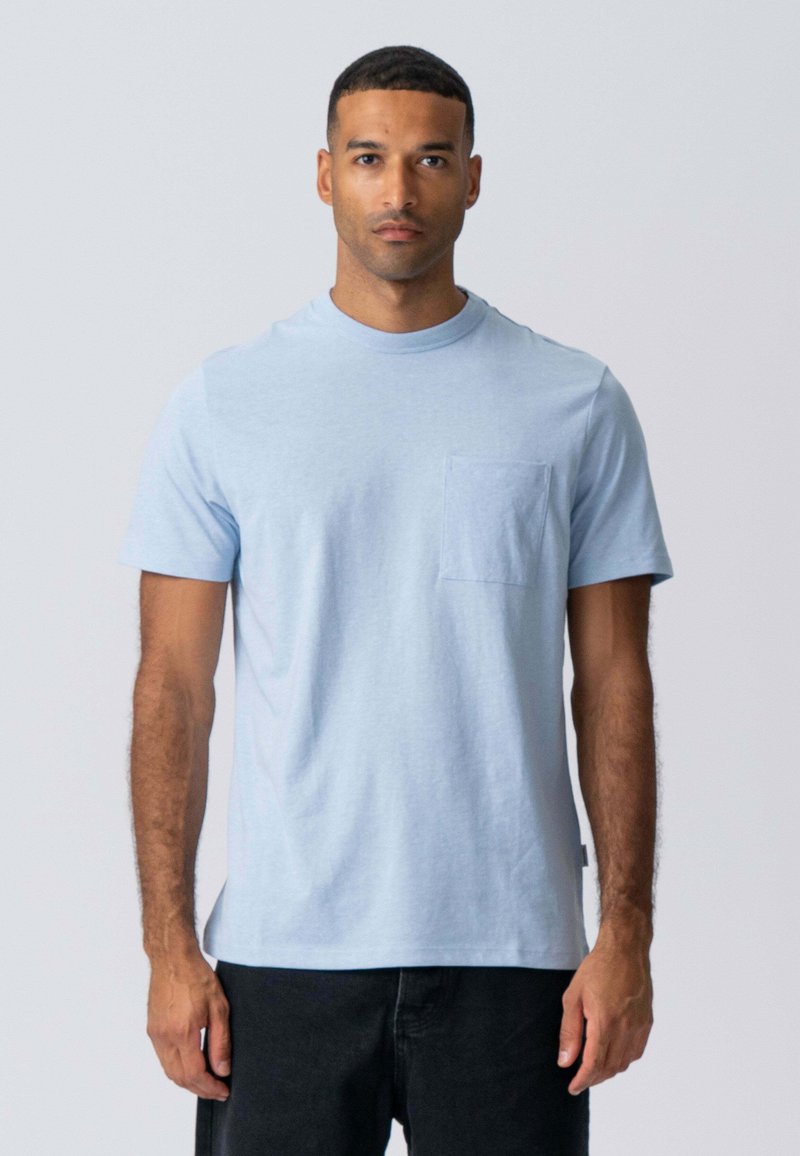 Lys blå kortærmet t-shirt i bomuld med rund hals og en brystlommer. Blød tekstur, afslappet pasform.