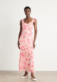 Pink floral dress with ruffles; lightweight fabric; sleeveless design; features rose patterns; floor-length; paired with white heels.
