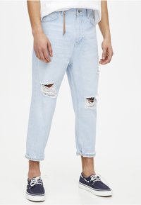 Ljusblå ripped jeans med slitna detaljer och en avslappnad passform. Utsmyckade med fransade knäöppningar och uppvikta nederkanter.