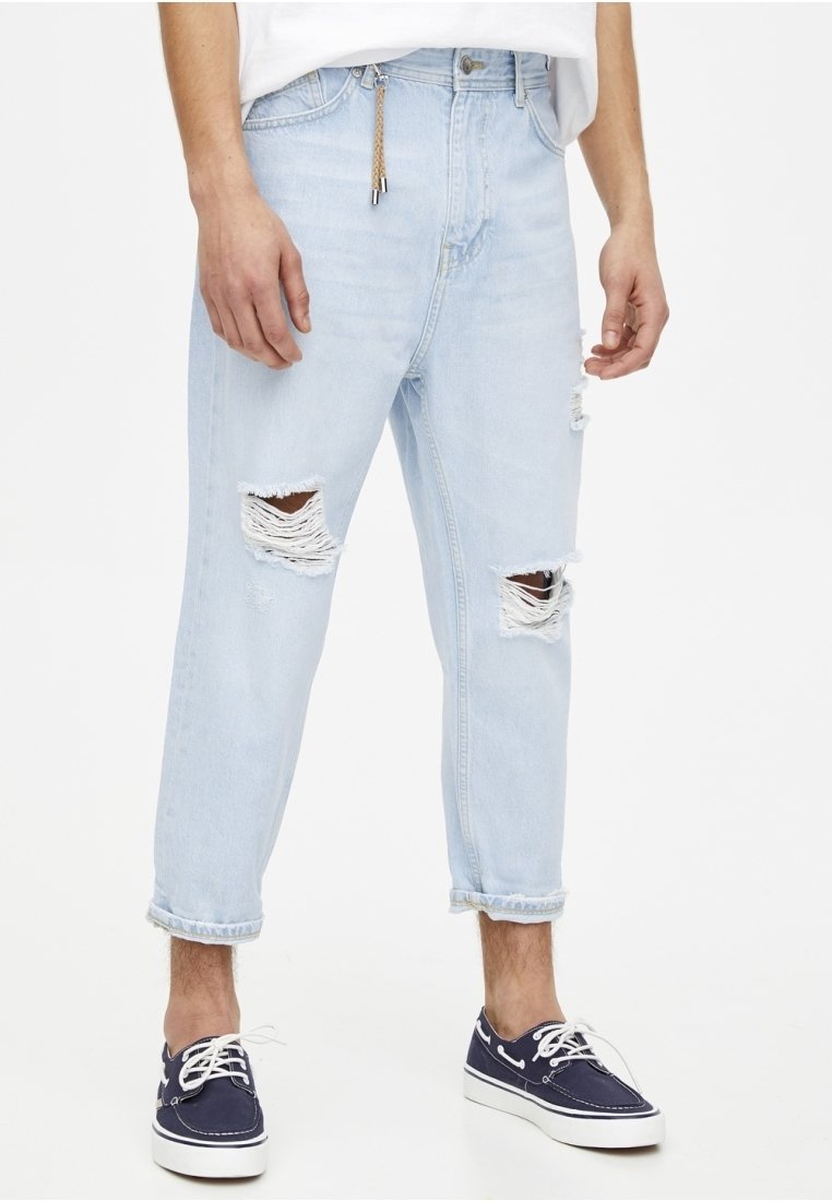 Ljusblå ripped jeans med slitna detaljer och en avslappnad passform. Utsmyckade med fransade knäöppningar och uppvikta nederkanter.