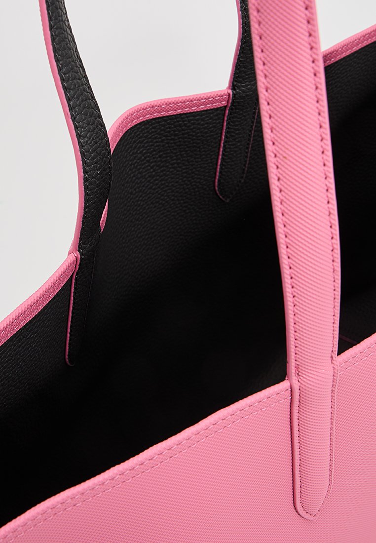 Rosa Tragetasche aus strukturiertem Material, schwarzes Innenfutter und kontrastierende rosa Kanten an den Trägern. Verfügt über Nahtdetails entlang der Kanten.