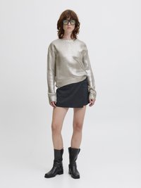 Μεταλλικό ασημένιο πουλόβερ, σκούρα υφασμάτινη μίνι φούστα και μαύρες μπότες με τακούνι μέχρι το γόνατο. Διαφάνειες μεγάλες γυαλιά ολοκληρώνουν την εμφάνιση.