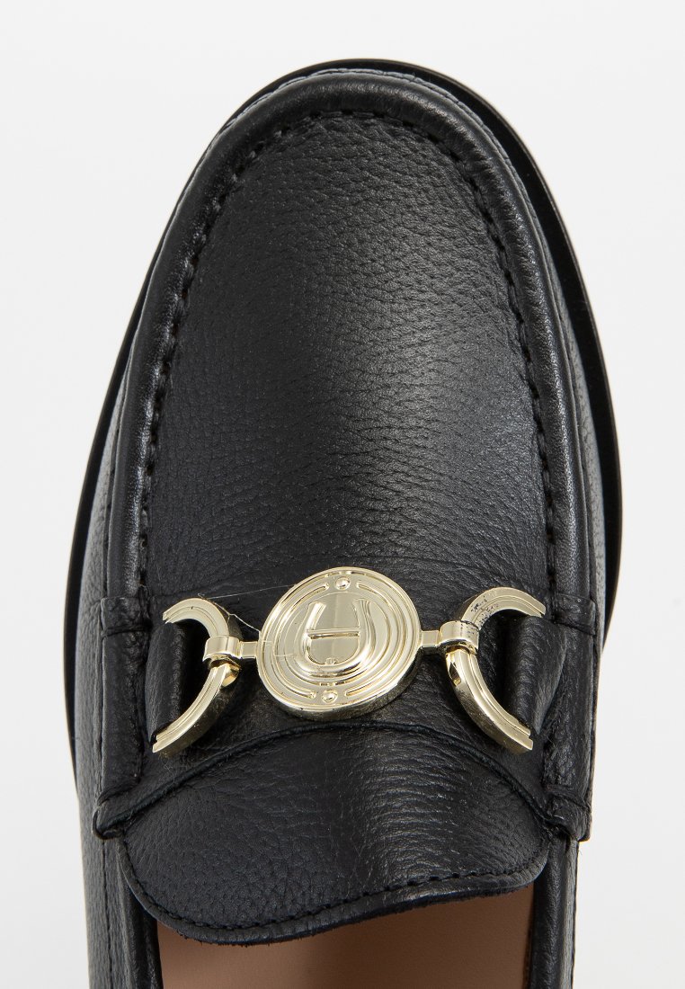 Czarne skórzane loafersy z zaokrąglonym noskiem, strukturalnym wykończeniem i złotymi detalami z przodu. Gładkie szwy podkreślające krawędzie.