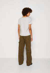Grey short-sleeve t-shirt with a rounded neckline, paired with loose olive green cargo pants featuring pockets and a textured fabric.