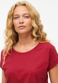 T-shirt rosso a maniche corte con scollatura rotonda, realizzato in tessuto morbido, caratterizzato da una vestibilità comoda e maniche arrotolate. Senza motivi o dettagli notevoli.