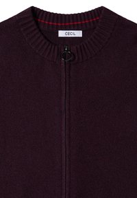 Cardigan lavorato a maglia viola con collo alto, interno rosso a contrasto e zip frontale con tab di apertura rotondo. Etichetta del marchio visibile.