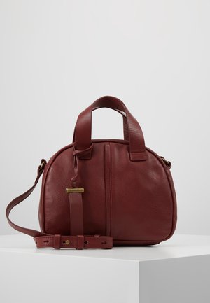 Bolso de mano de cuero marrón texturizado con asas cortas, correa de hombro ajustable y detalle de costura vertical, colocado sobre una superficie blanca.