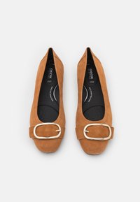 Brązowe baleriny zamszowe z szeroką, metaliczną złotą klamrą z przodu, o teksturowanej powierzchni i miękkiej czarnej wkładce.