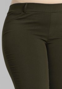 Olijf groene fitted broek van gladde stof met een subtiele glans, voorzien van een middenhoogte taille, zijzak en platte naden voor extra detail.