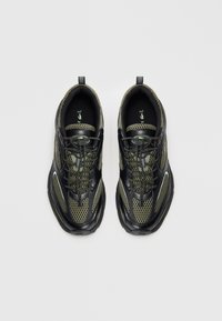 Pair of black and olive green athletic sneakers with mesh upper and toggle lacing, viewed from above on a white background.