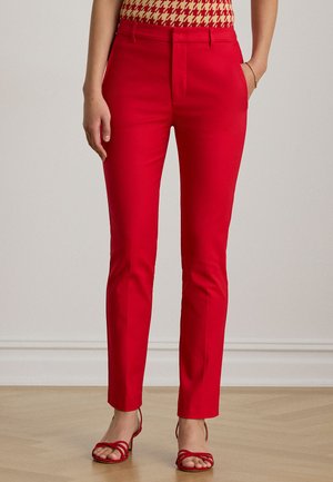 Pantaloni rossi su misura con una texture liscia, vestibilità slim e vita a metà altezza. Abbinati a sandali rossi con cinturini, che mostrano una silhouette pulita ed elegante.