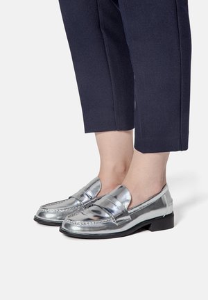 Metallic sølv loafers med en glat finish, lav hæl og dekorativ bånd over vampen. Stylet med cropped navy bukser.