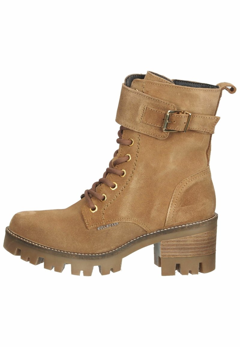 Bottine en daim beige avec talon épais, lacets à l'avant, bride à boucle et semelle robuste pour une meilleure adhérence.