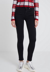 Jeans skinnies negros de denim, con un diseño clásico de cinco bolsillos. Combinados con zapatillas plateadas de suela gruesa y un suéter recortado a cuadros.