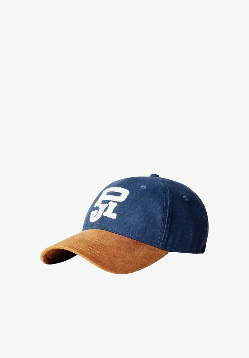 Casquette de baseball avec couronne bleu marine et visière courbée en suède marron, ornée de lettres stylisées blanches brodées sur le panneau avant.