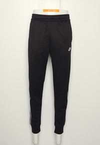 Černé bežecké kalhoty Nike s bílými bočními pruhy, elastickým pasem a zúženými kotníky vystavené na trupu mužského manekýna.