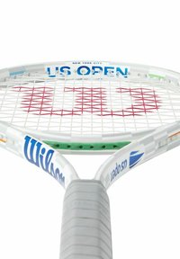 Raqueta de tenis Wilson US Open, marco blanco, cuerdas rojas con un gran logo, empuñadura texturizada en gris y acentos coloridos.